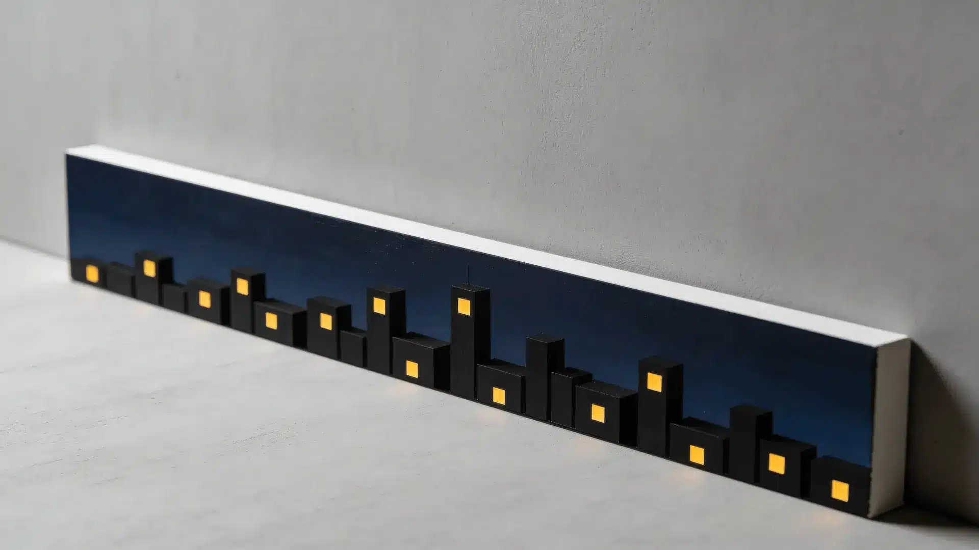 Canvas with dark skyline of rectangular buildings and small yellow window dots