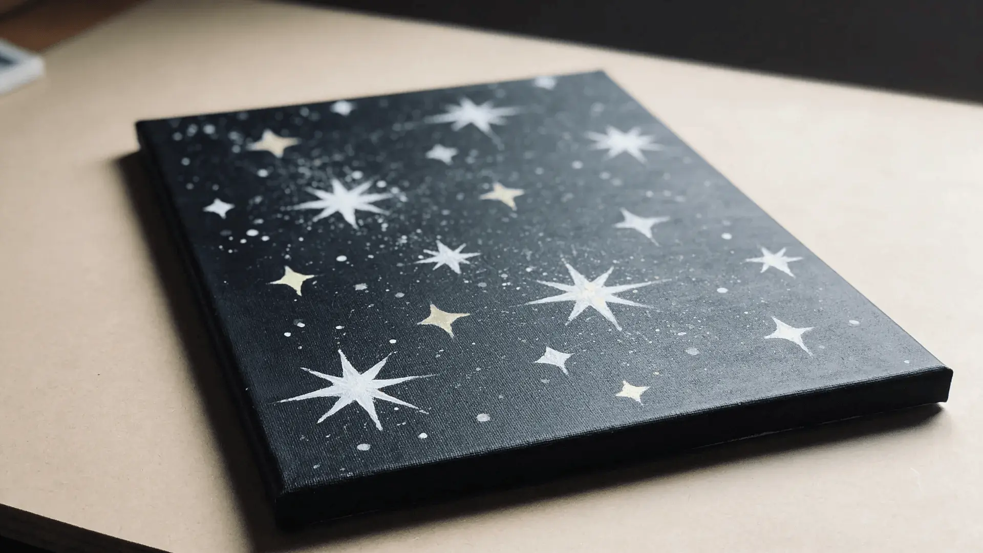 Dark canvas with white paint splatters resembling stars