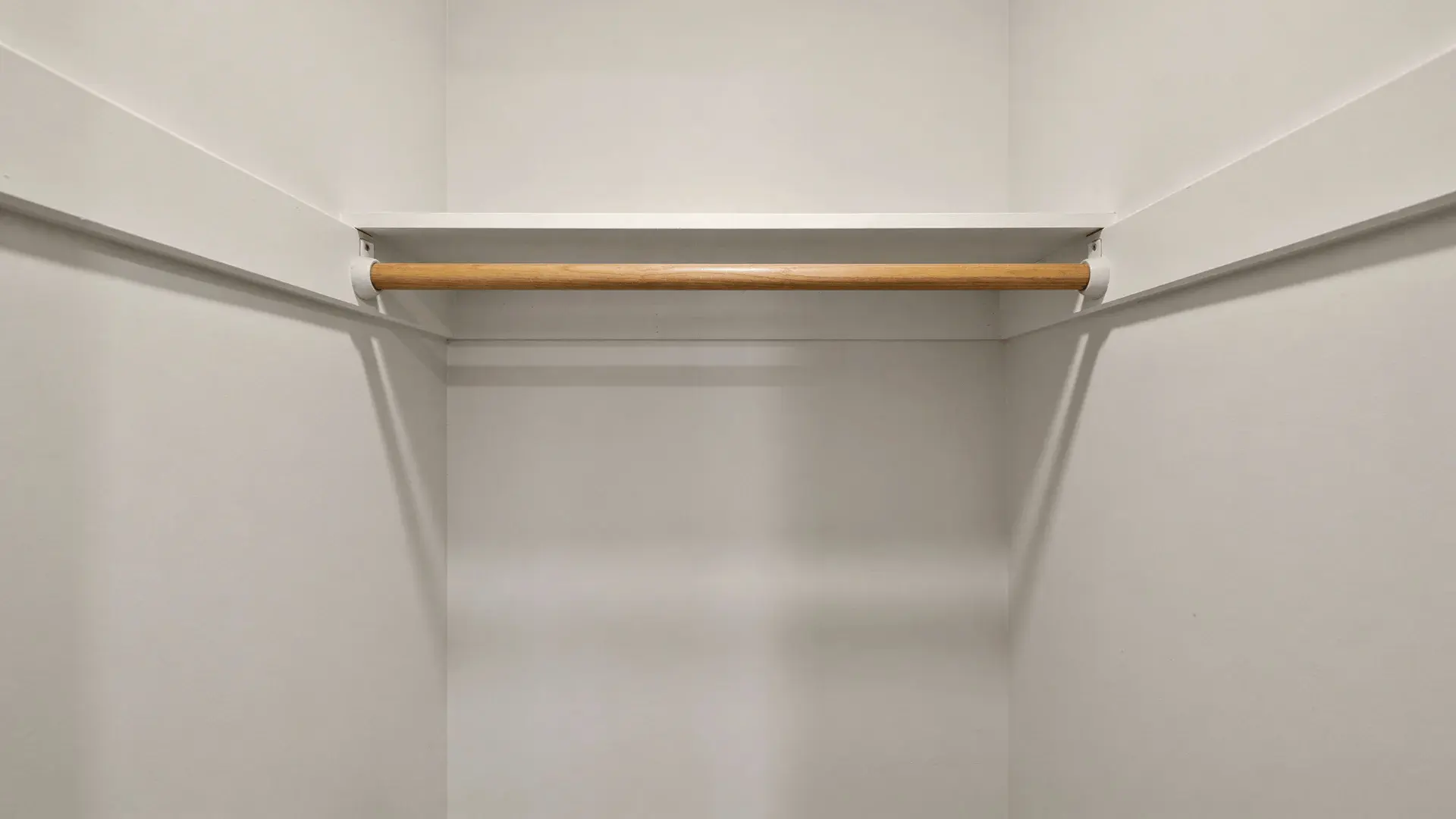 Empty reach-in closet with hanging rod and top shelf