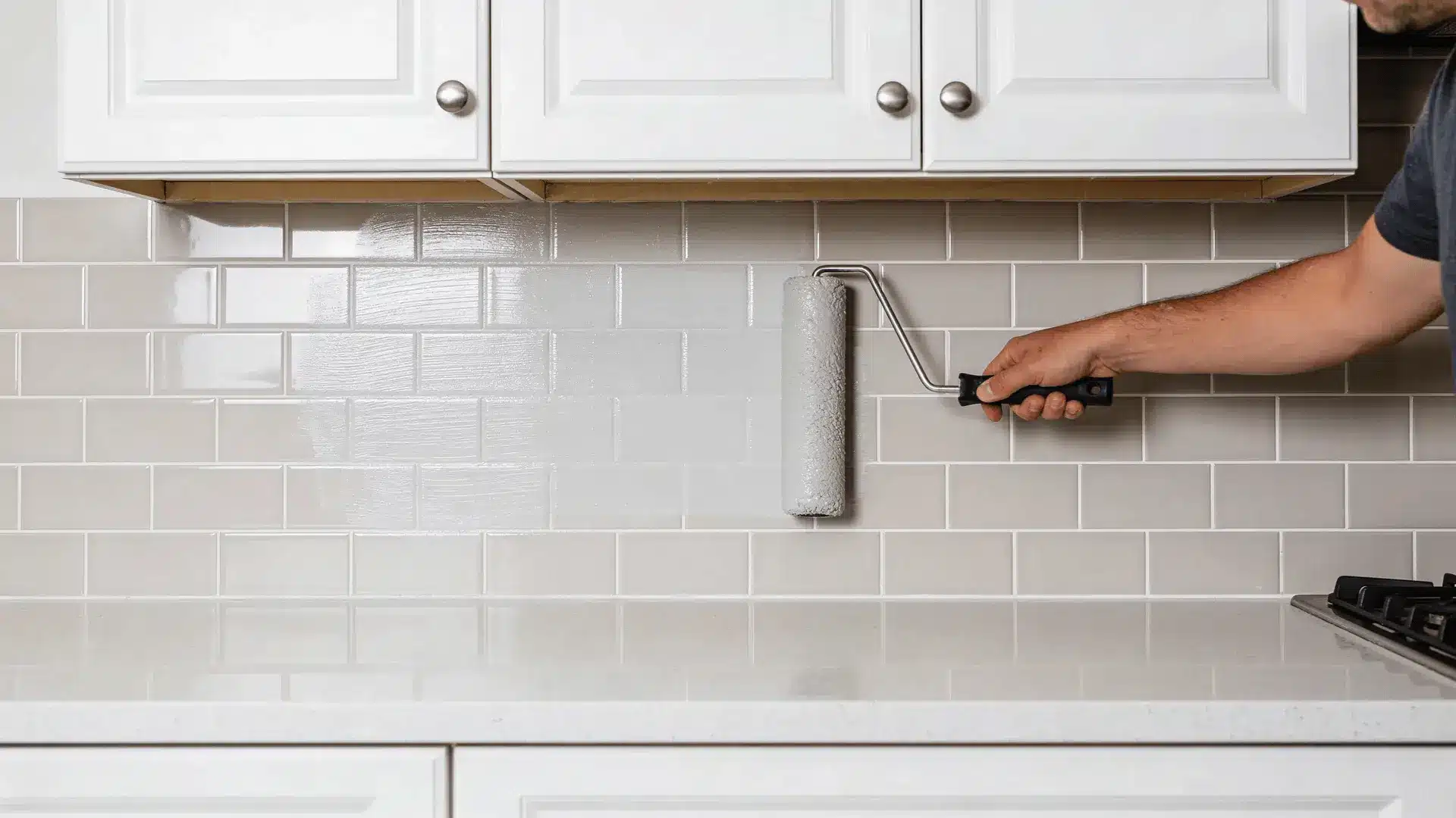 Person rolling clear topcoat over painted tile backsplash
