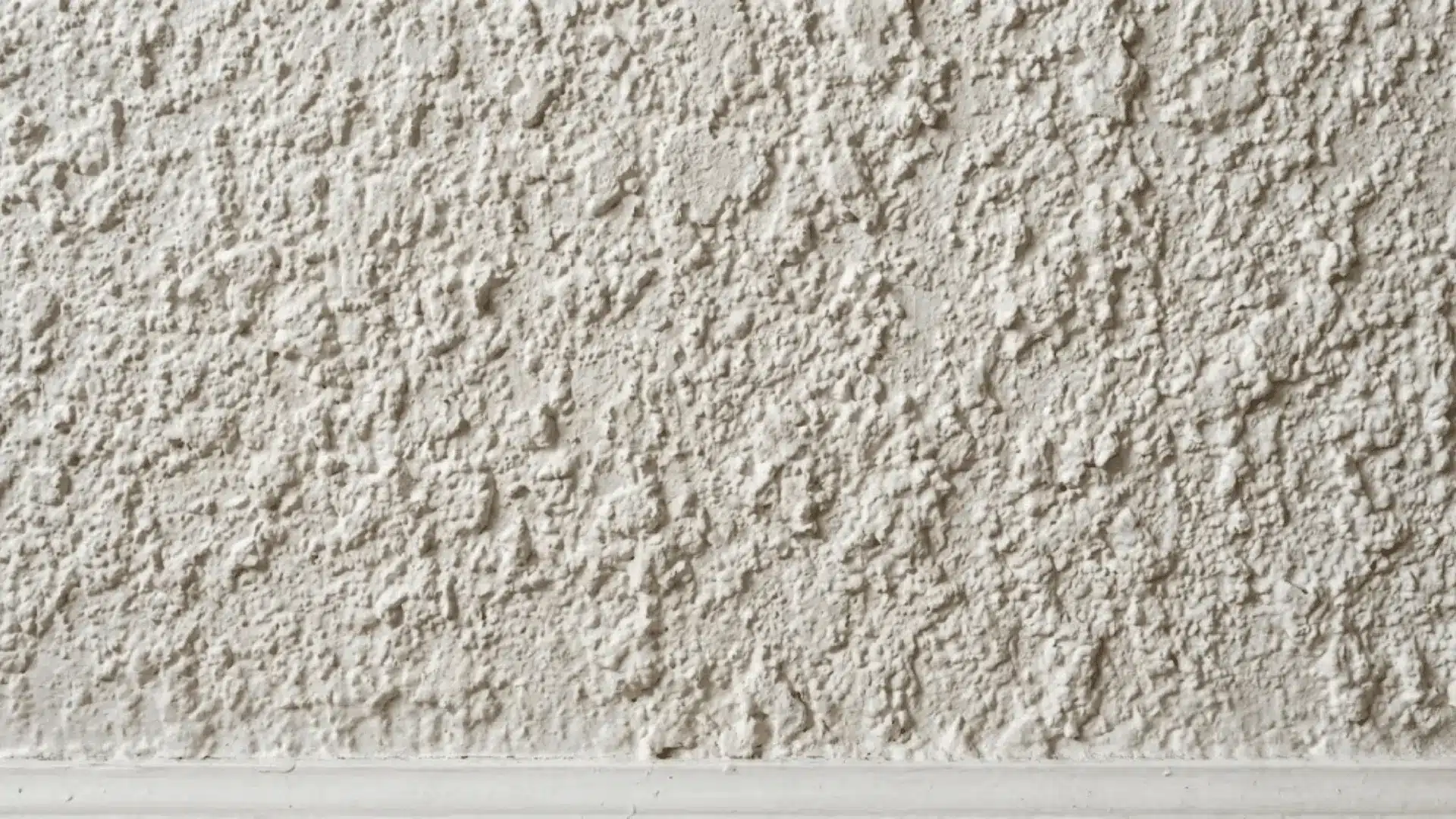 close-up of a heavily bumpy popcorn texture wall surface in sharp natural light