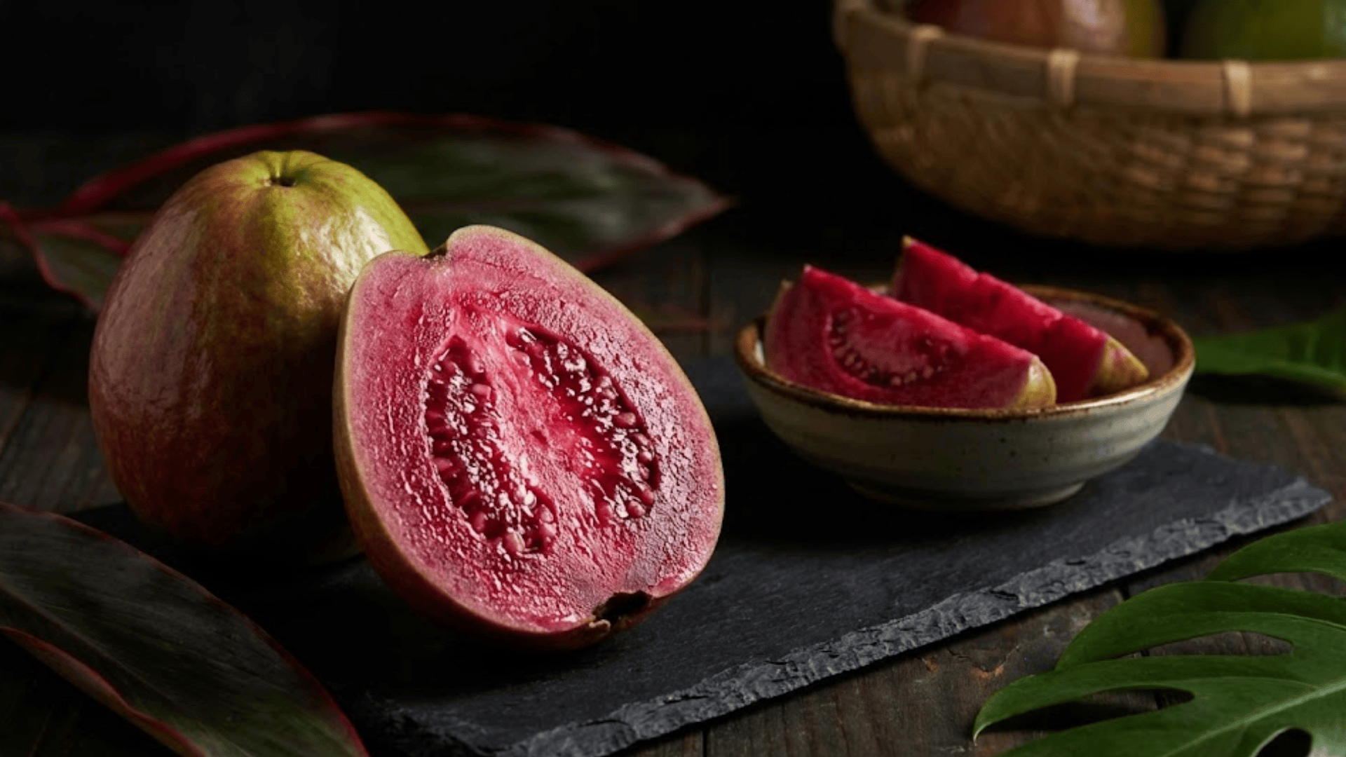 red malaysian guava showing deep burgundy flesh on dark slate board