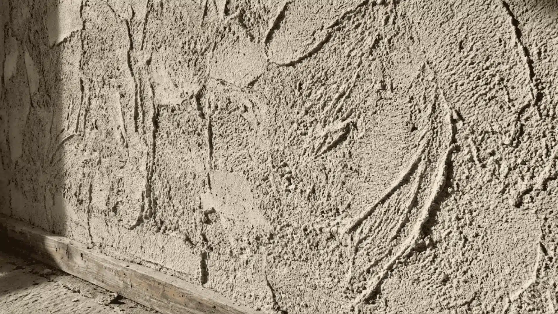 rough heavy stucco and sand texture on an interior wall photographed in sharp natural light