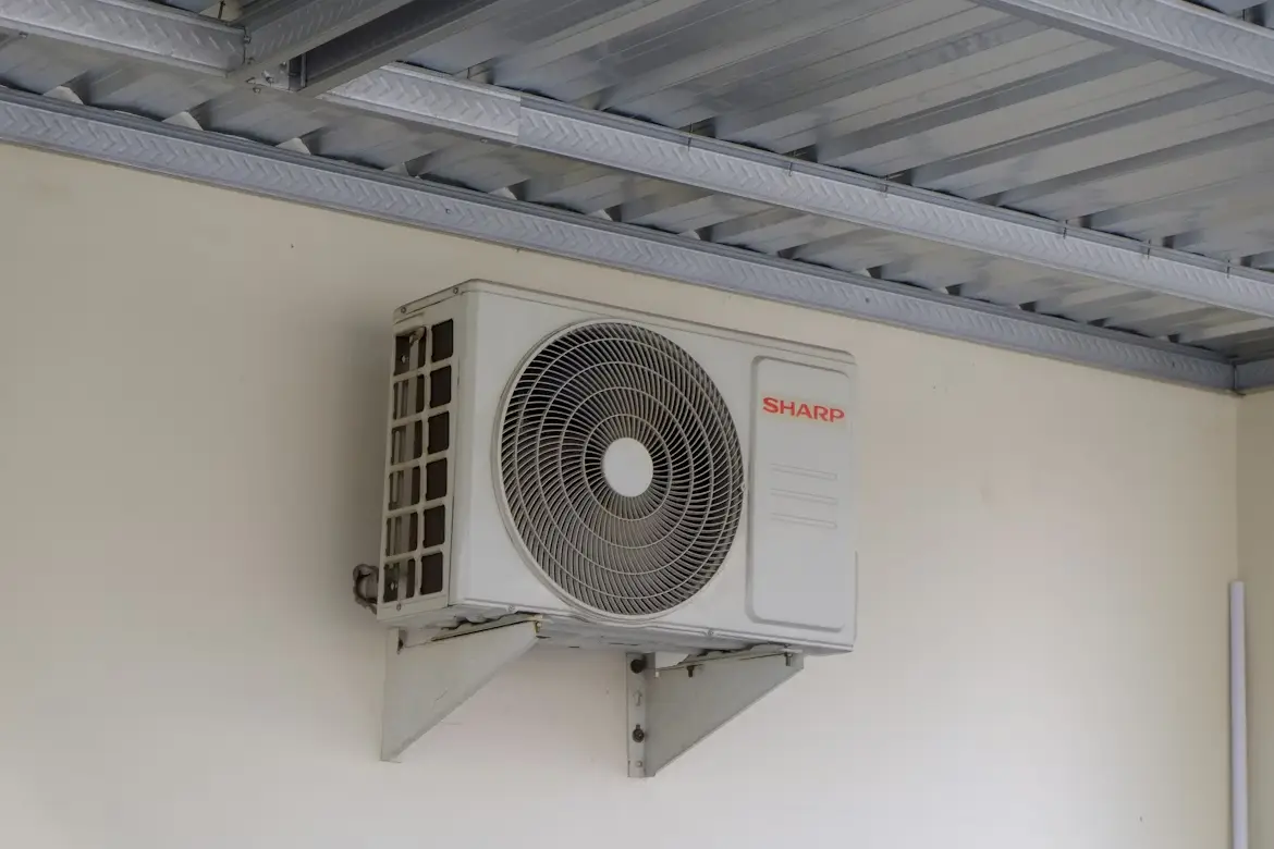 Outdoor air conditioning unit mounted on a beige wall under a metal roof structure