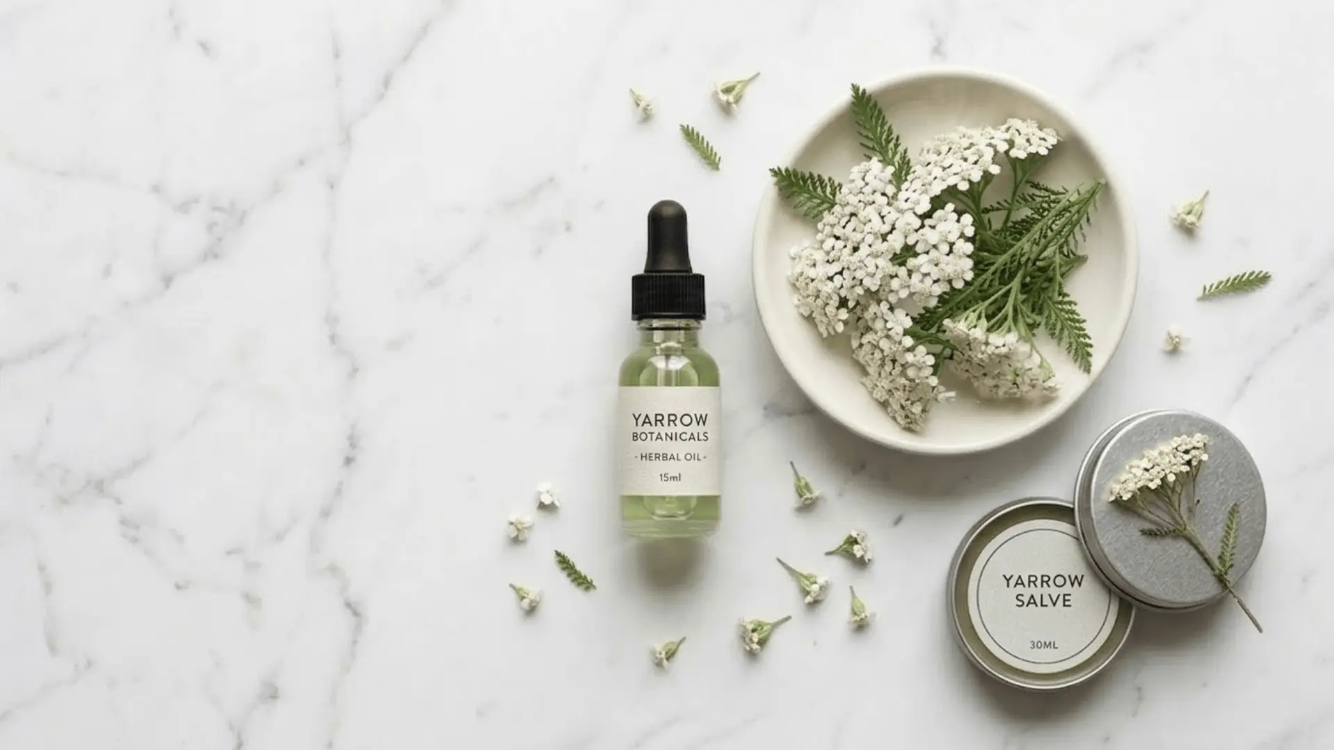 yarrow flowers and herbal skincare products on marble surface showing yarrow benefits for skin