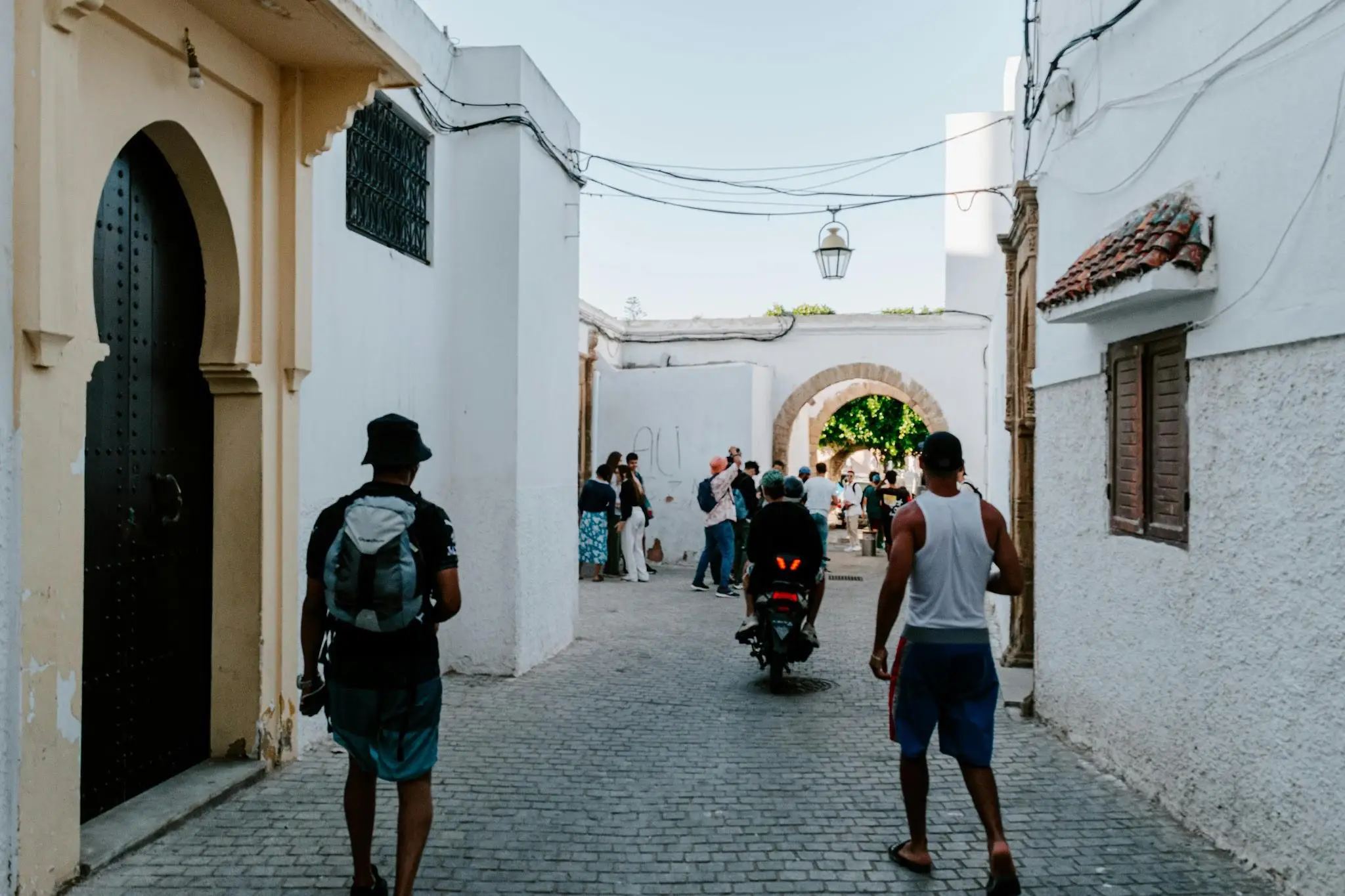 Narrow cobblestone street with people and motorbike in quaint Mediterranean town setting