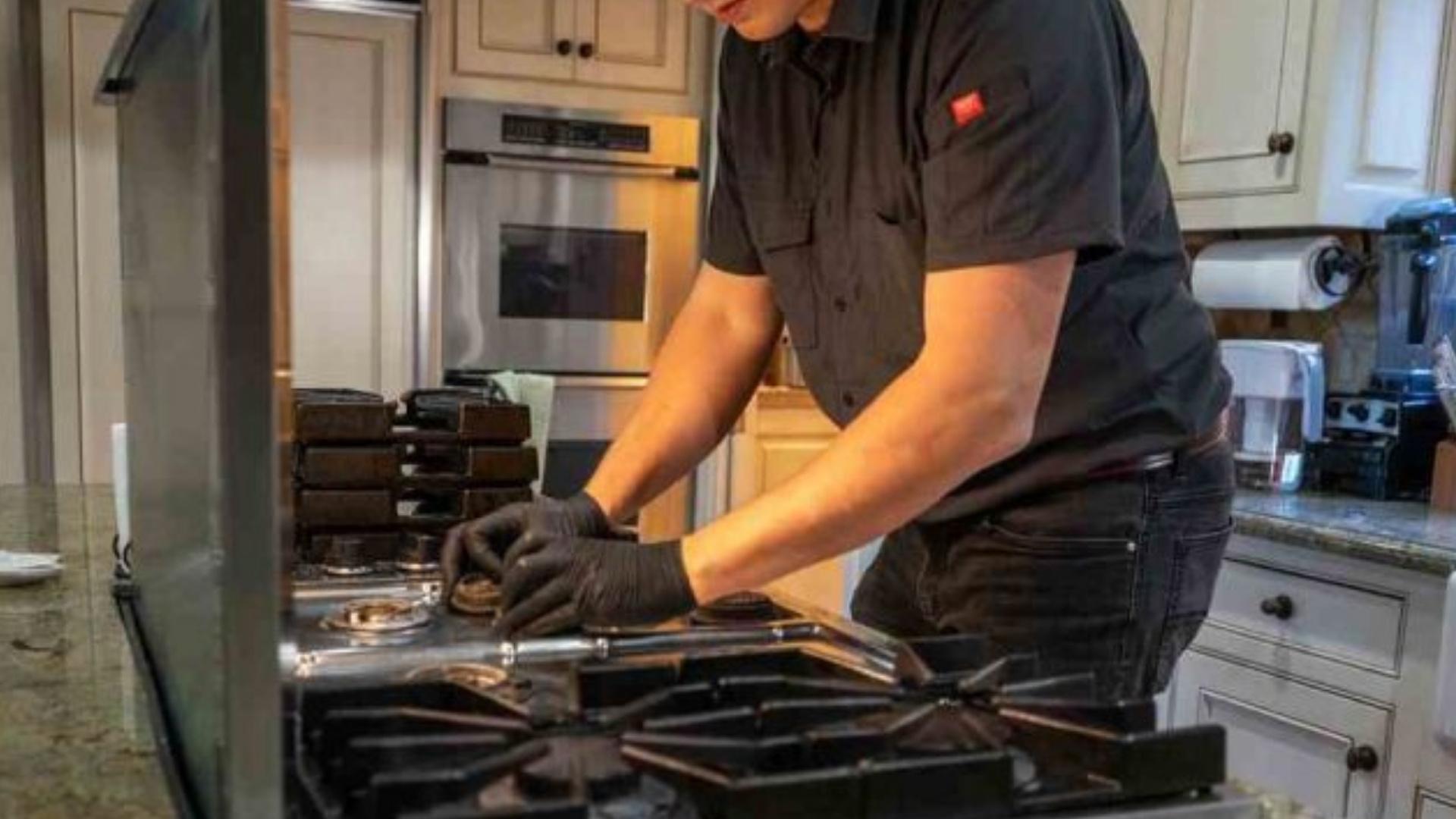 PrimeFix Technician repairing a kitchen cooktop with tools in a modern home kitchen