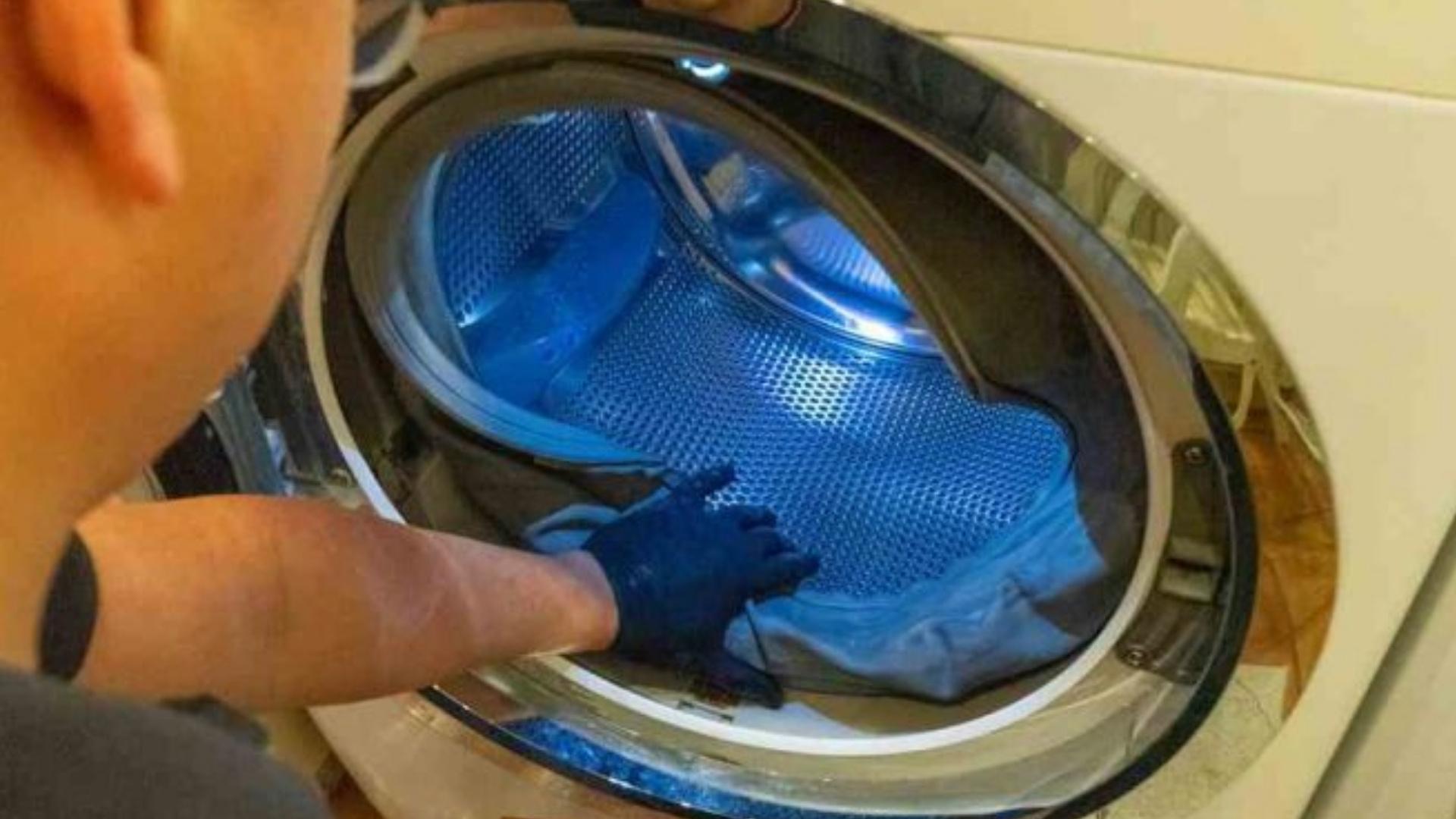 PrimeFix Technician inspecting inside a front-load washing machine drum during repair