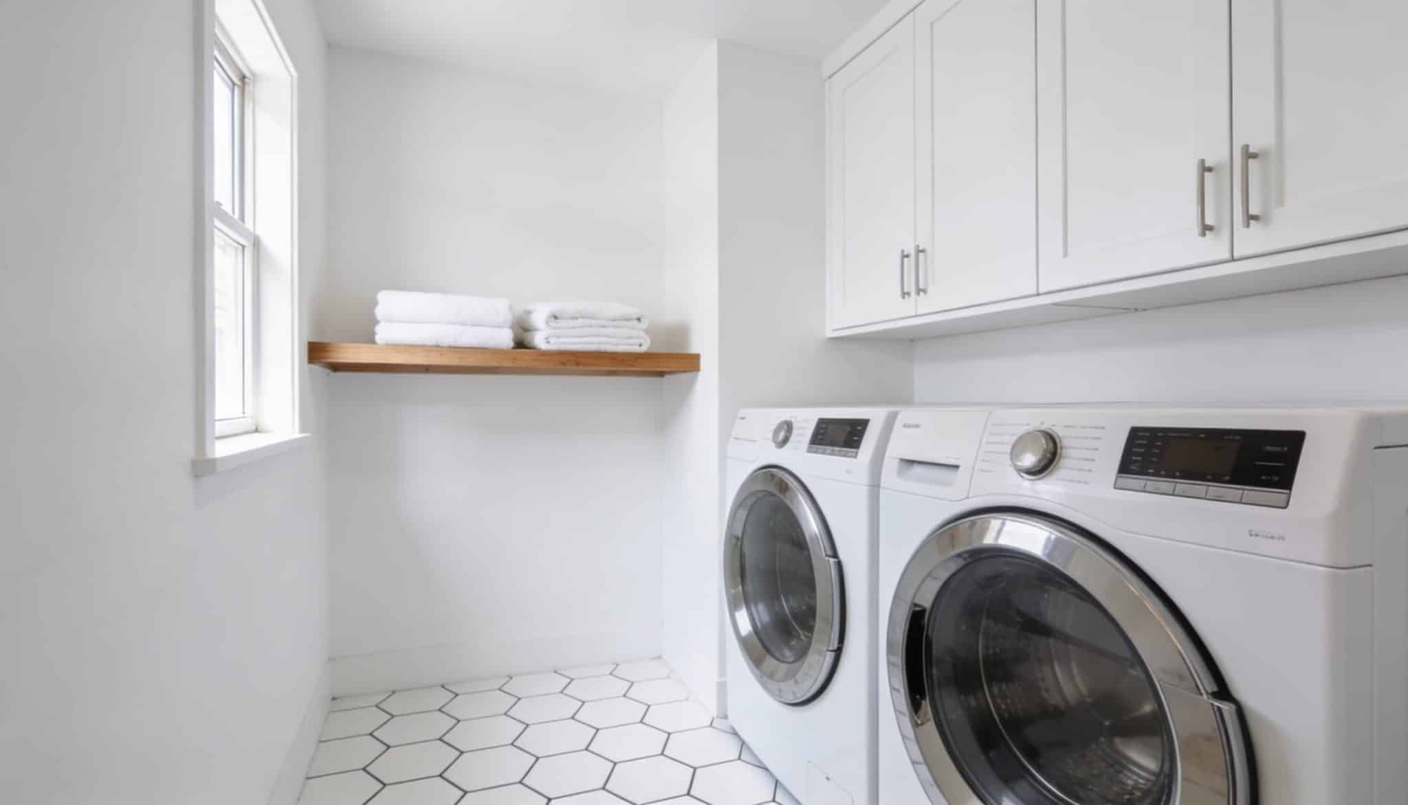 A bright laundry room with white walls, white cabinetry, and a clean, minimalist aesthetic.
