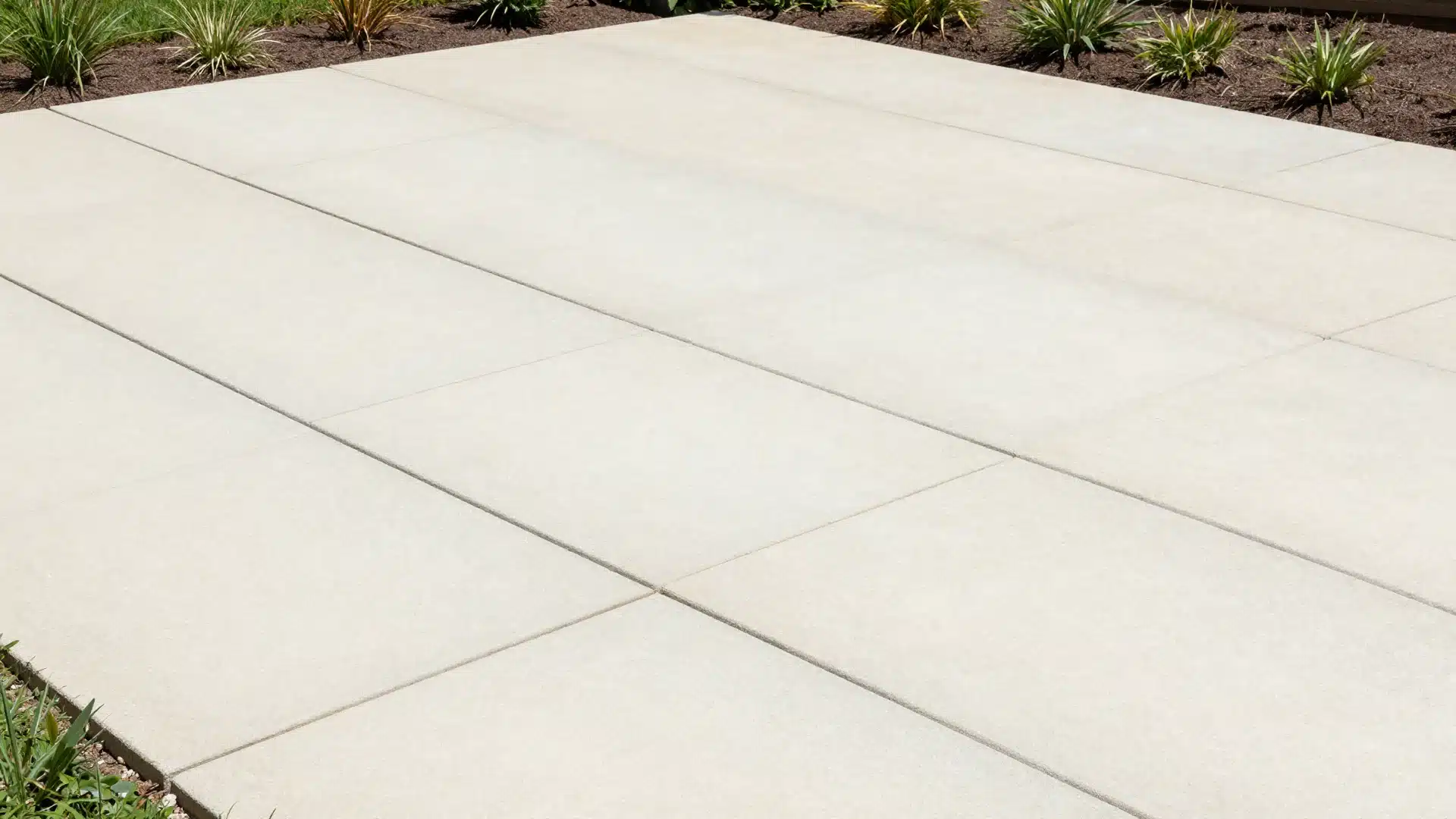 A small patio area featuring large, light-colored concrete pavers with clean, minimal grout lines that make the space look expansive.