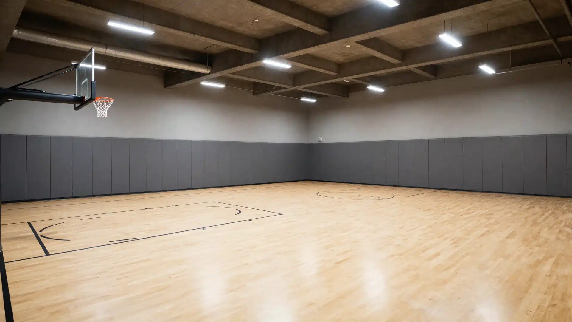 A spacious basement converted into an indoor sports court with professional-grade flooring, basketball hoops, and bright lighting