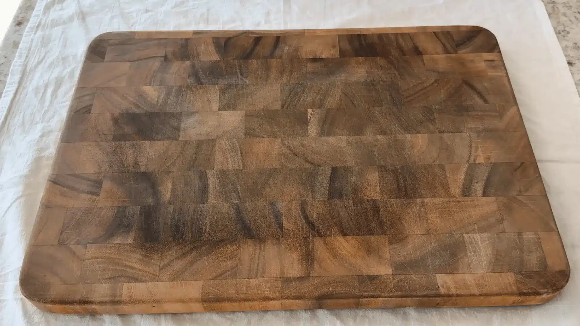a dry wooden cutting board with visible discoloration and dullness before oiling and conditioning