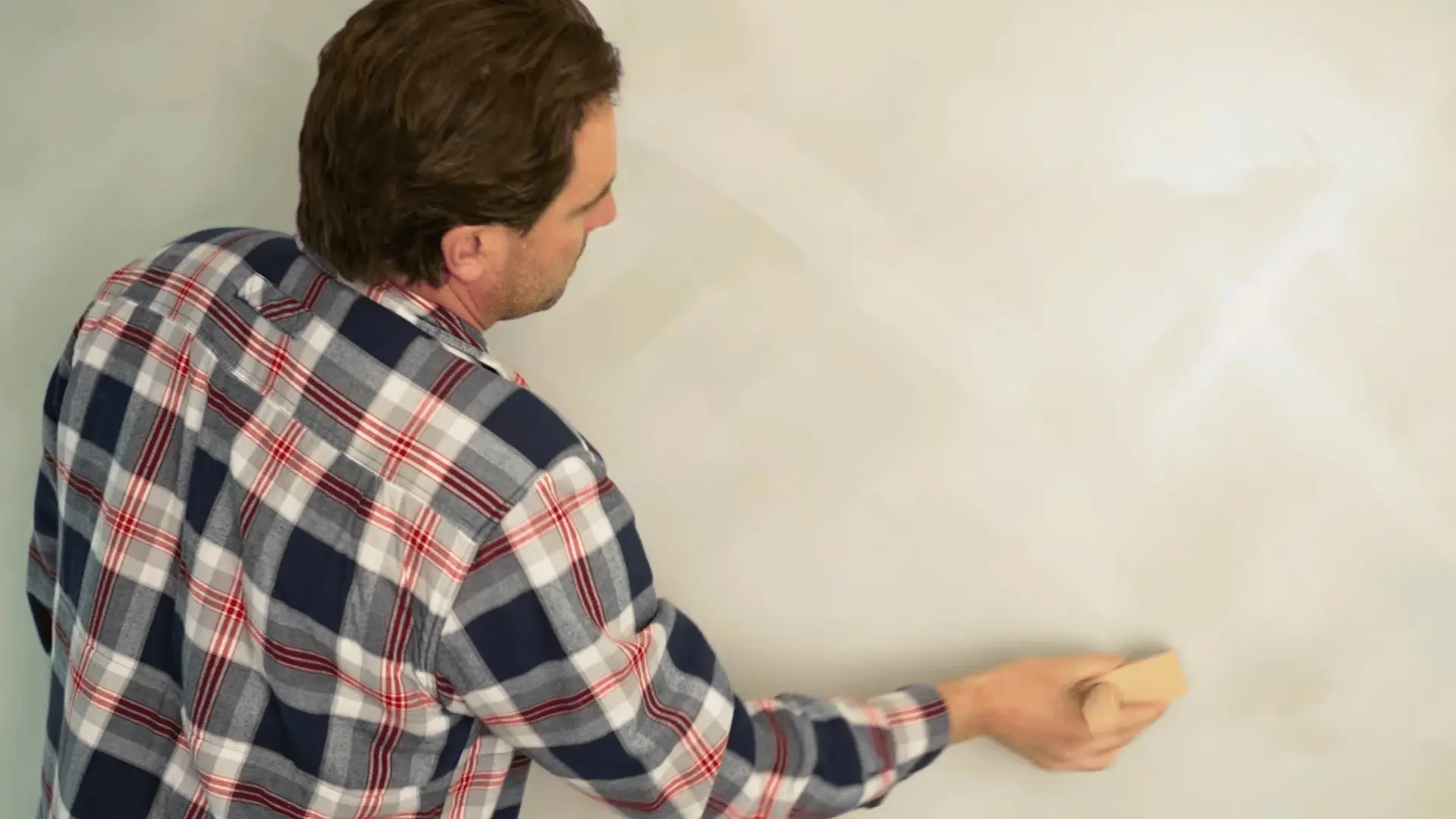 a person blending the second coat of limewash paint on a wall for a smooth layered finish