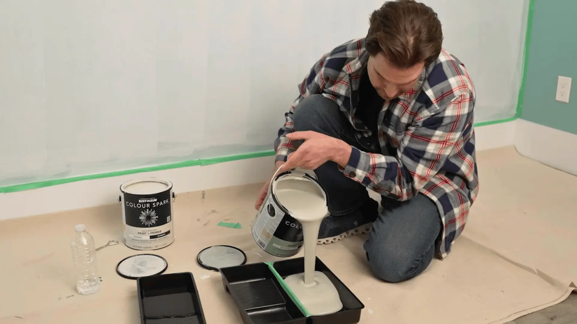 a person pouring rustoleum colour spark paint into taped-together trays for a limewash wall project