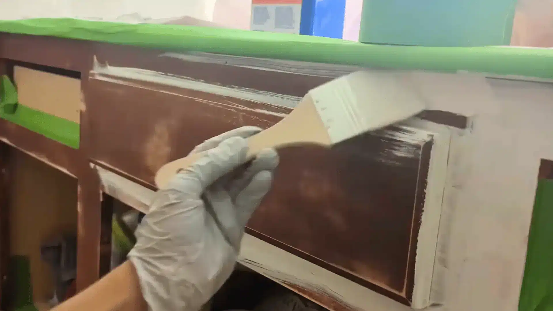 applying bonding primer to a bathroom vanity cabinet with a paintbrush and painter's tape along the edges