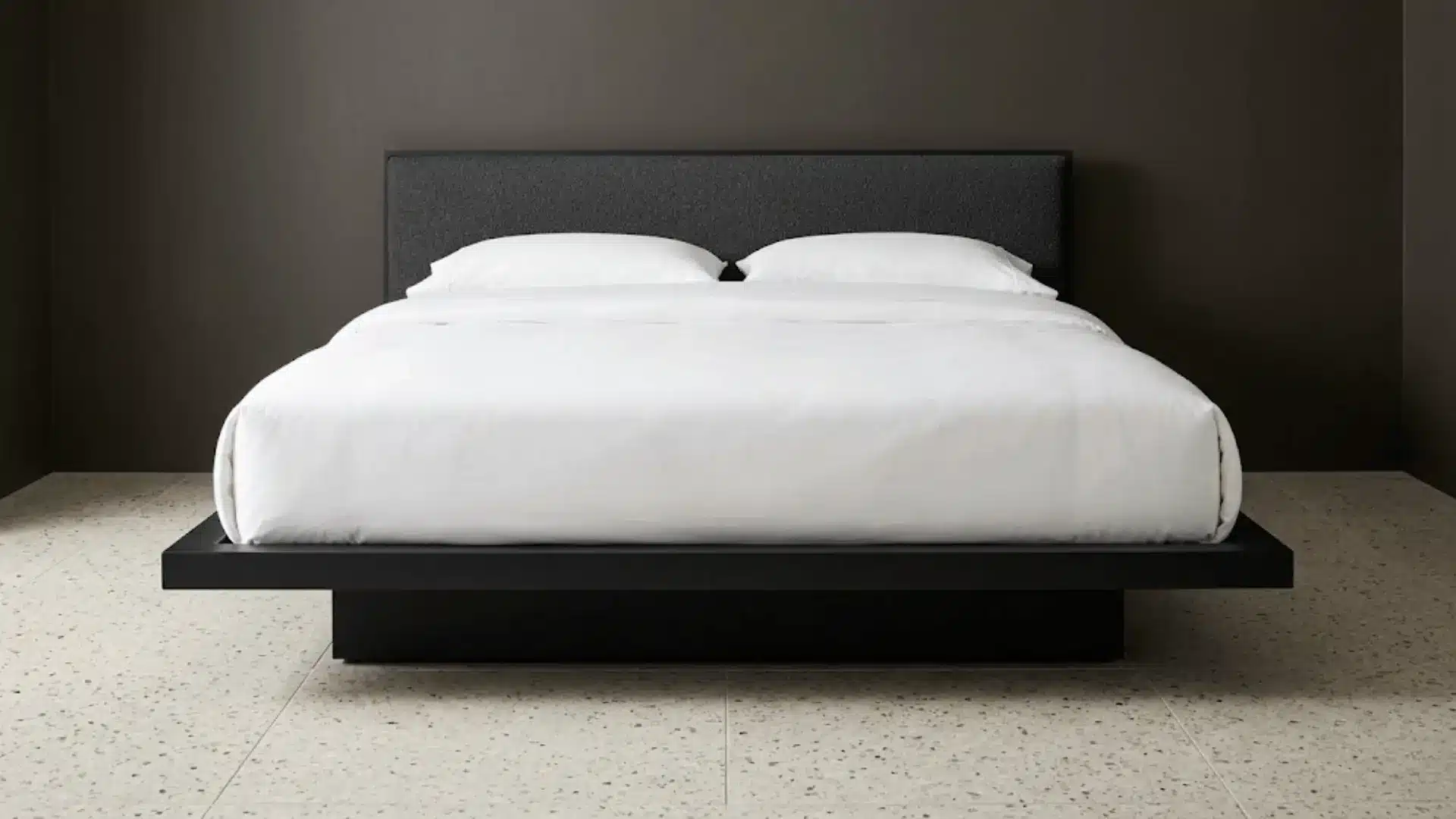 floating platform bed in matte black with boucle headboard hovering above a terrazzo floor