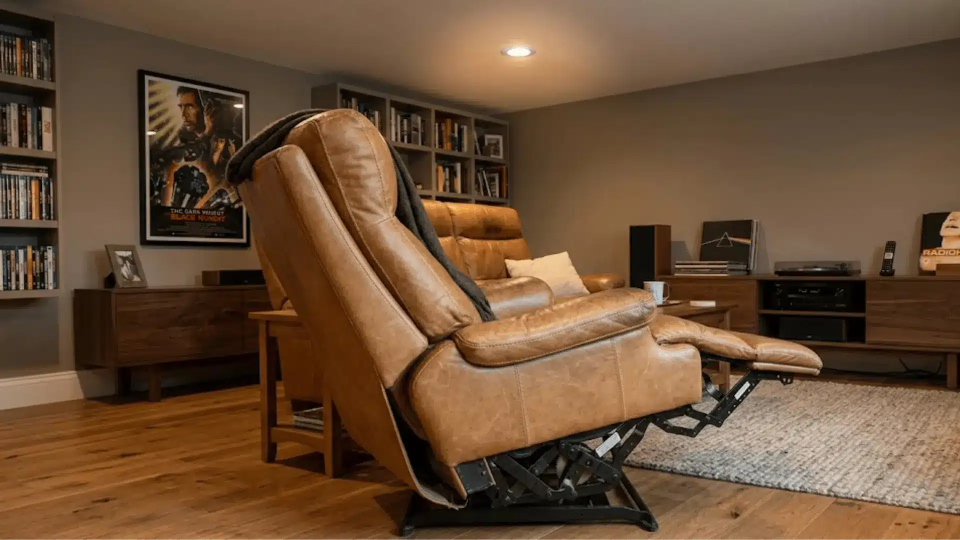 full-grain tan leather recliner in a warm home media room with hardwood flooring and soft overhead light