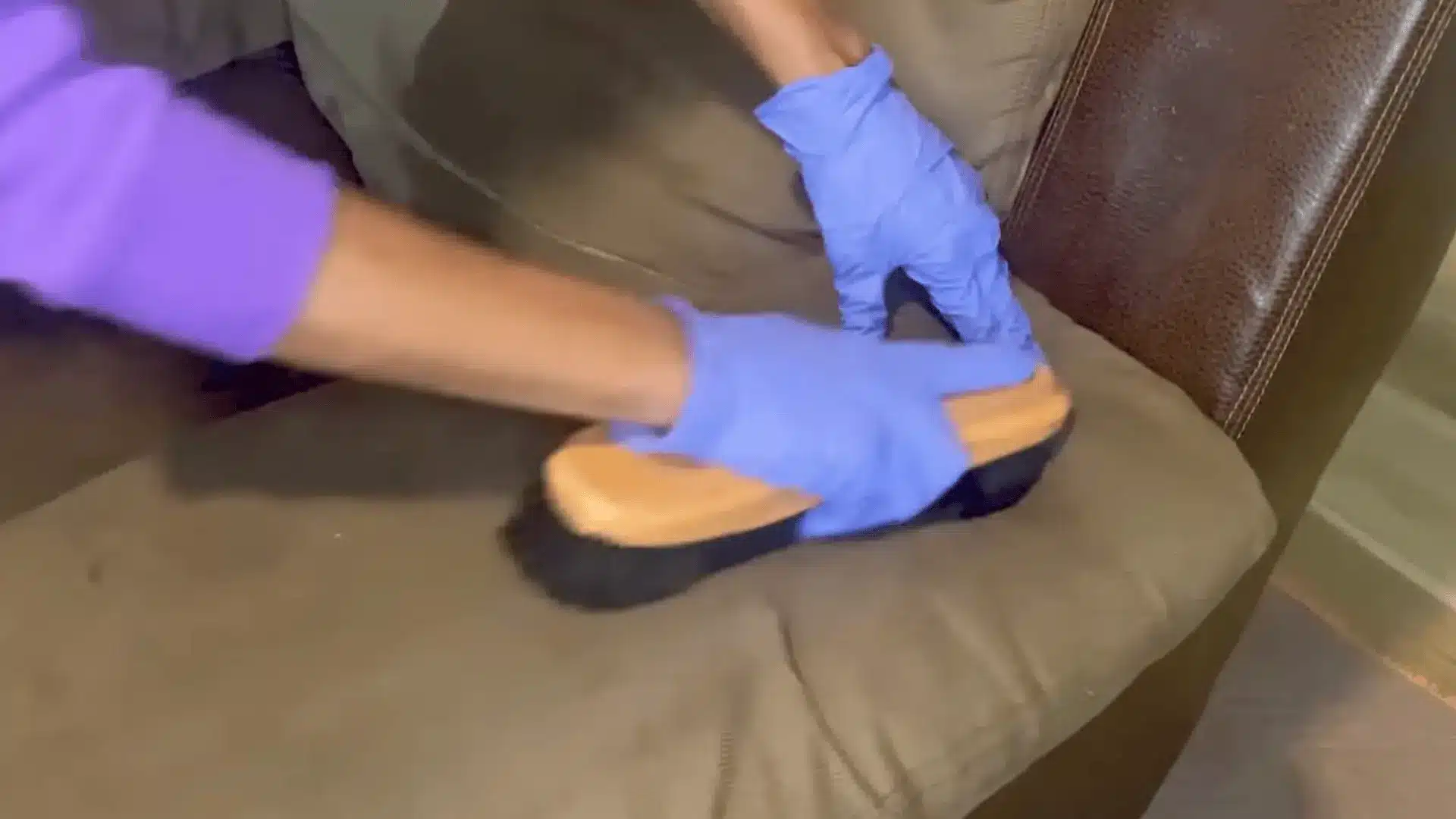 gloved hands scrubbing a beige fabric couch cushion with a soft-bristled brush