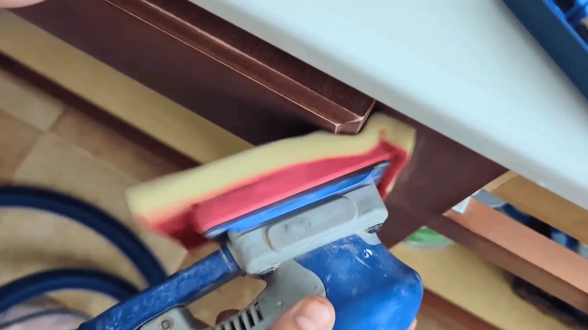 sanding the edges of a bathroom vanity cabinet door with a foam sanding tool before painting