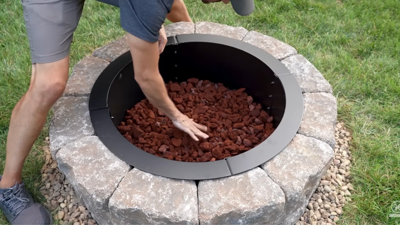 builder filling the inside bottom of the fire pit with lava rocks, pea gravel, or regular gravel