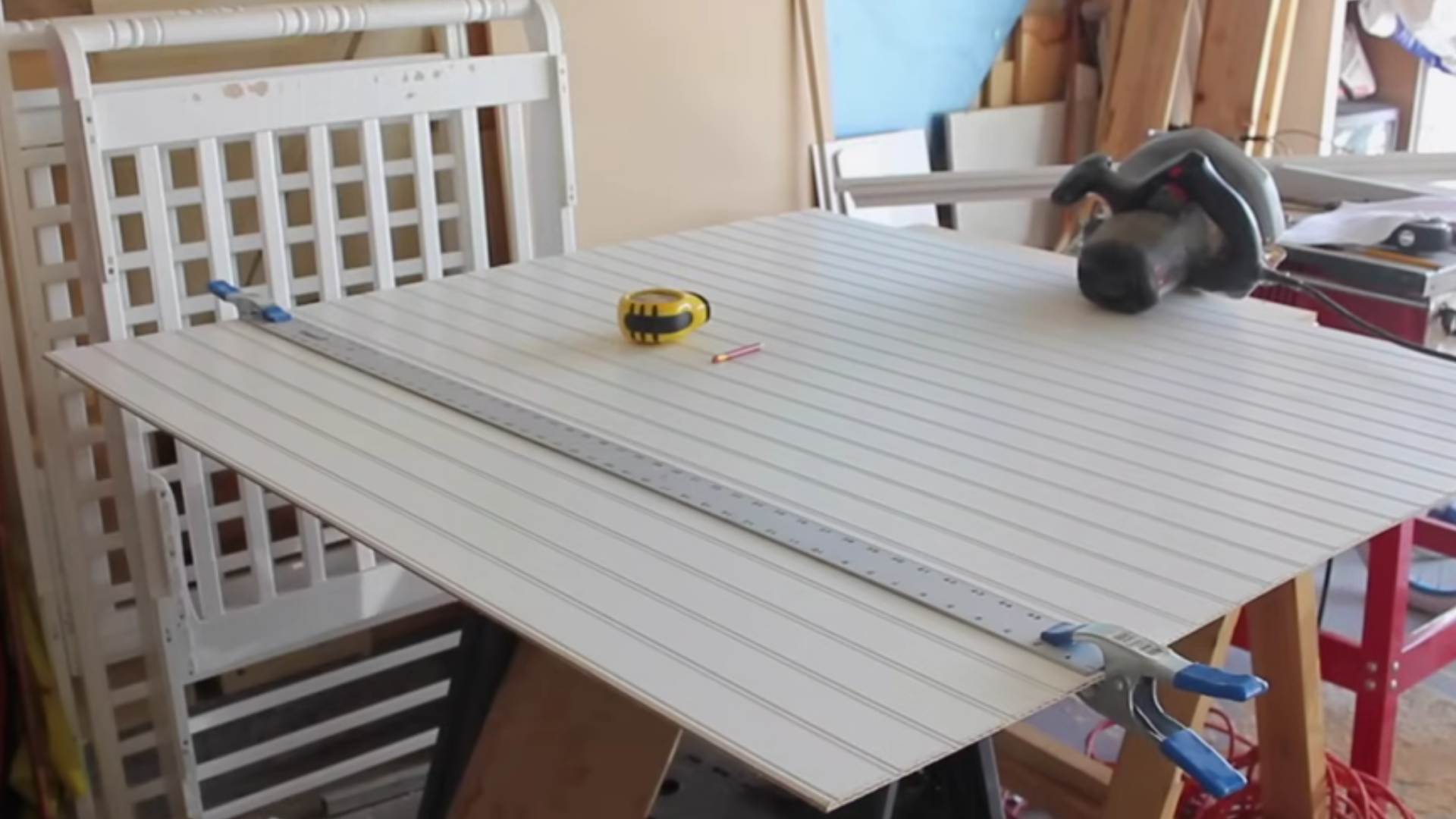 cutting a beadboard sheet to wall size with a saw and guide for a straight clean edge before fitting