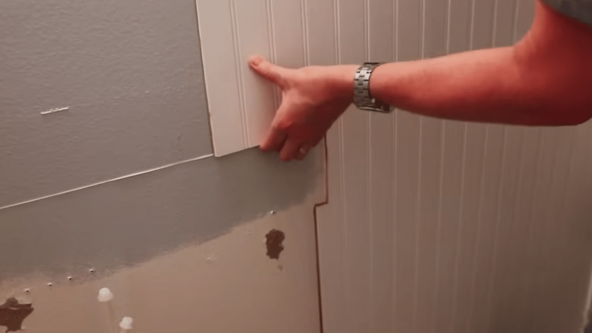 fastening a fitted beadboard panel to the wall with nails placed near edges top and bottom for support