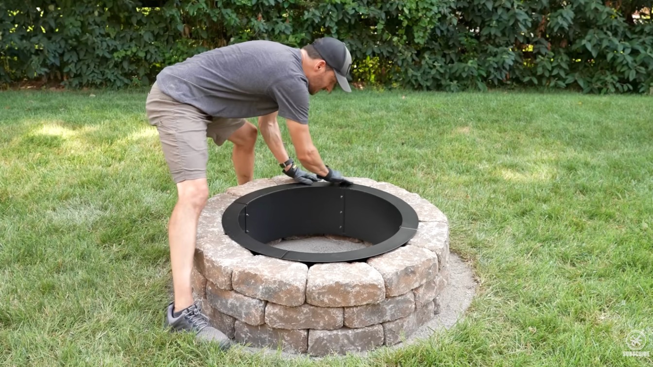 diy backyard ideas showing a finished stone fire pit with a metal insert in a green backyard space at home
