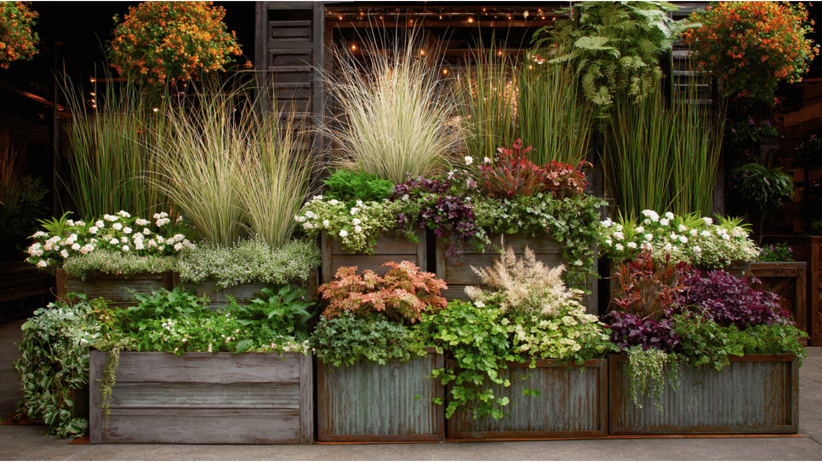 layered garden containers filled with grasses vines flowers and leafy plants creating rich textures and natural depth