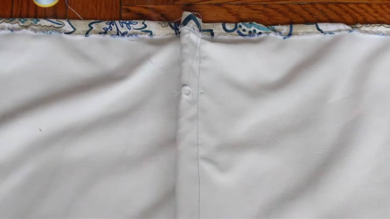 plastic rings sewn in a neat row on white lining fabric for a diy roman shade cord setup at home