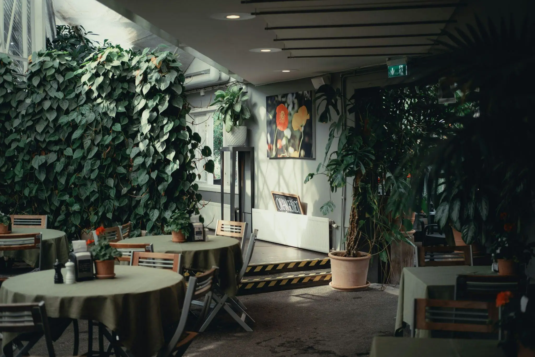 Indoor garden café with round tables, potted plants, and lush greenery under natural light