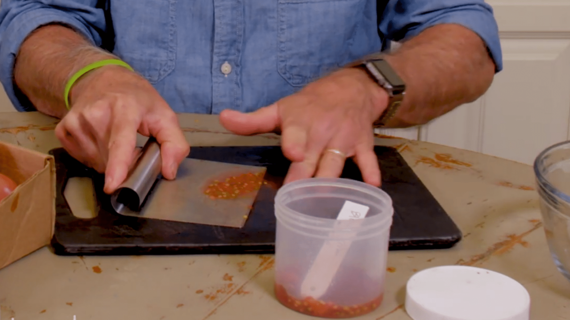hands collecting tomato seeds with pulp into separate jar with name and date label
