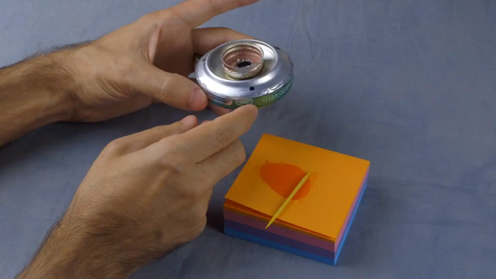 hands holding a modified beverage can with a bottle cap attached beside epoxy on colorful sticky notes