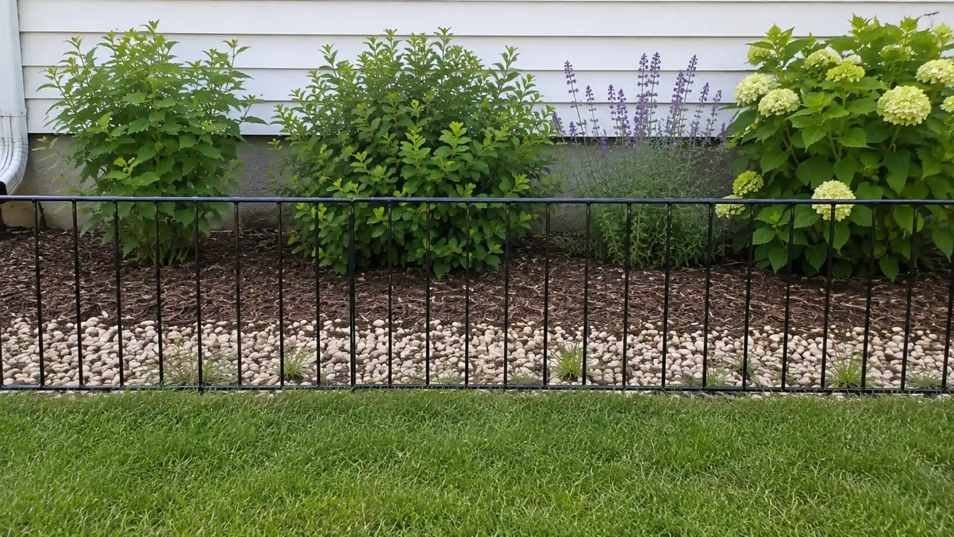 black metal border fence lining a mulch and rock garden bed
