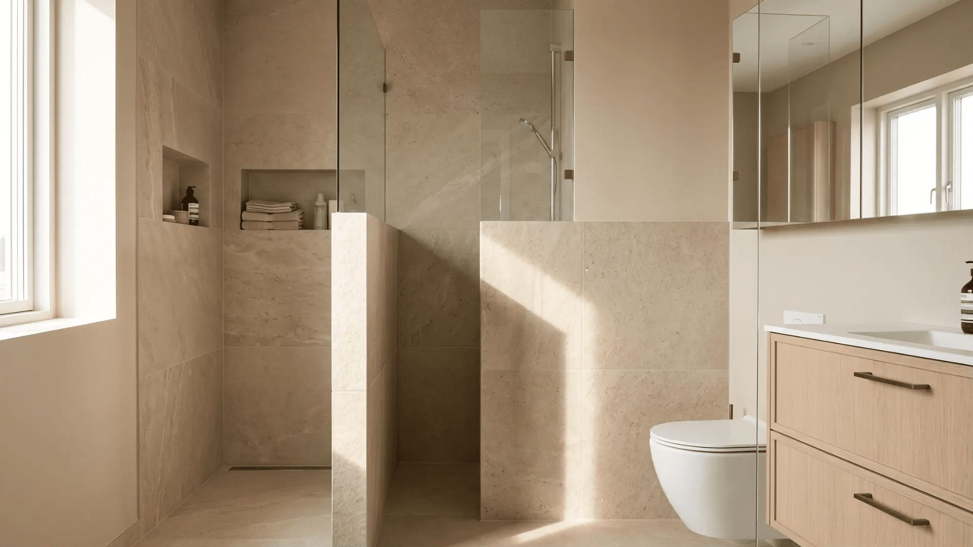 doorless shower with tiled privacy half-wall beside toilet and vanity