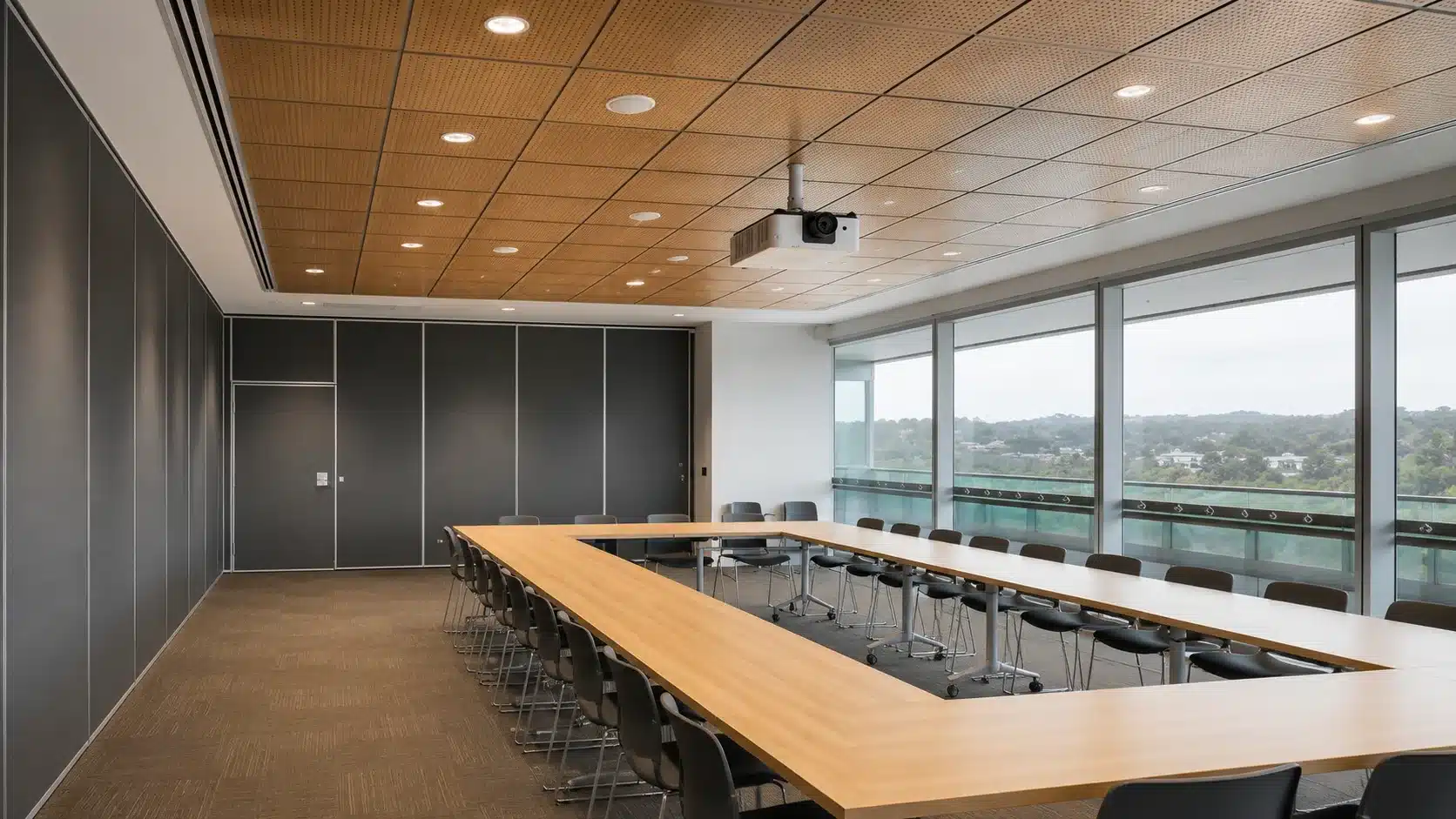 modern conference room with acoustic ceiling tile panels projector and long tables beside large windows