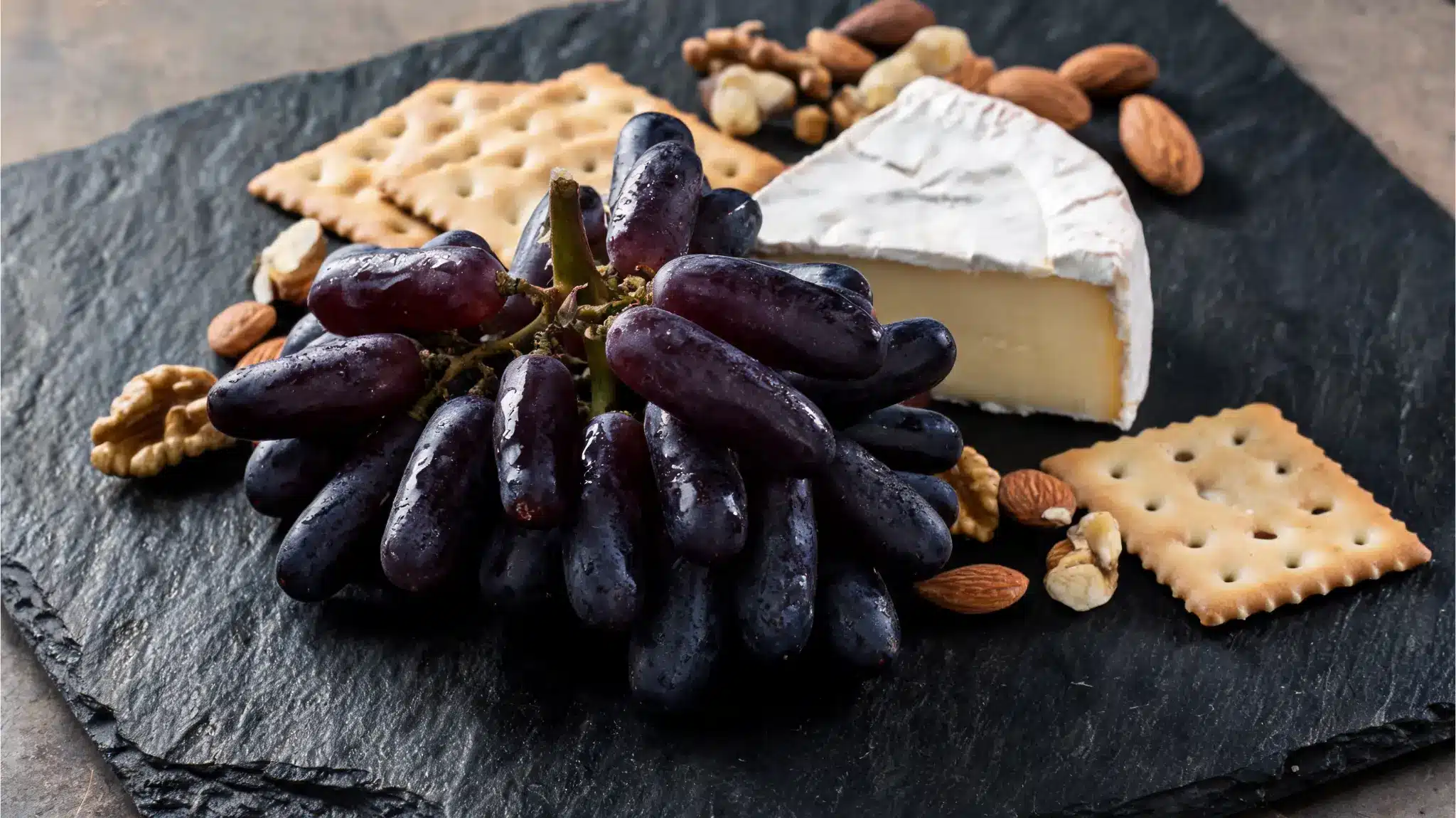 moon drops grapes on a cheese board with crackers and cheese