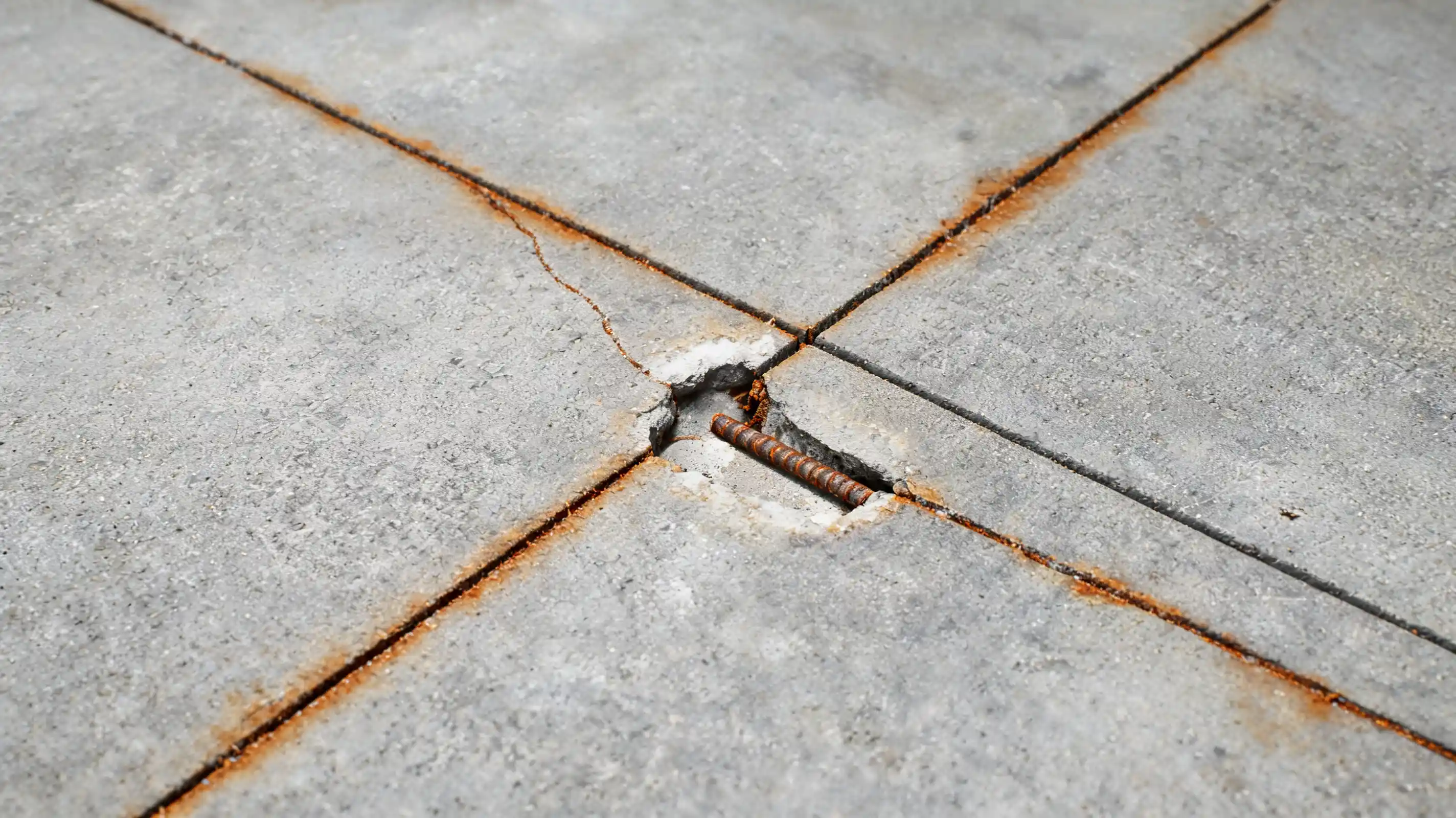 straight rebar cracks with rust stains and light surface damage on a concrete garage floor