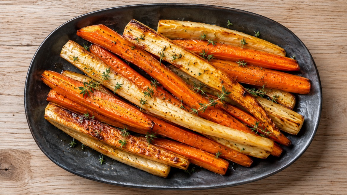 winter vegetables roasted carrots and parsnips with thyme on a black platter for a simple dinner side dish