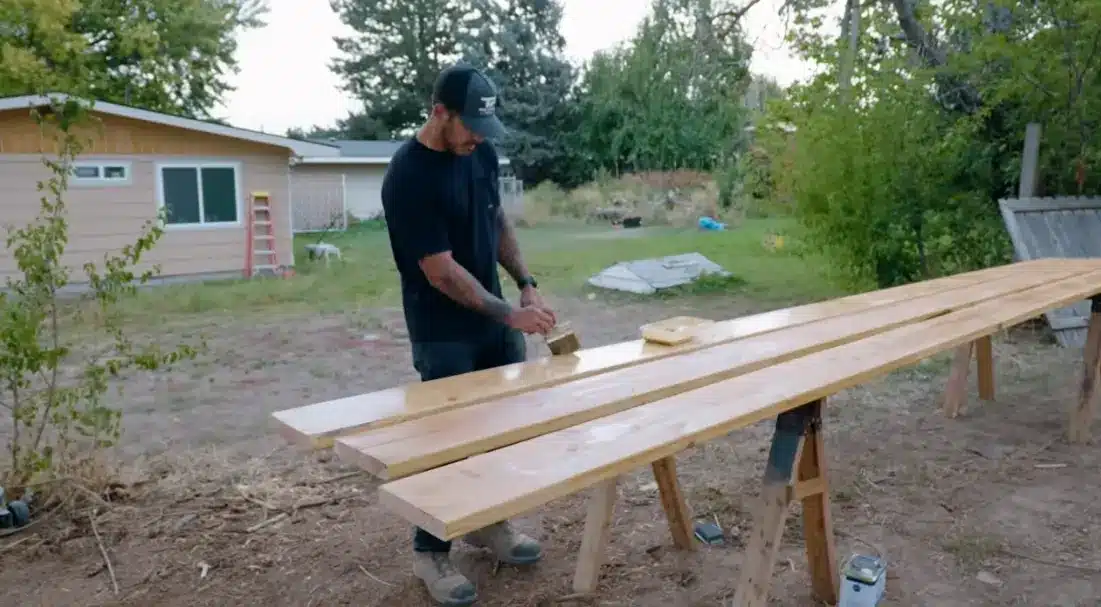 applying wood stain or sealant to the pergola lumber to protect it from weather and moisture