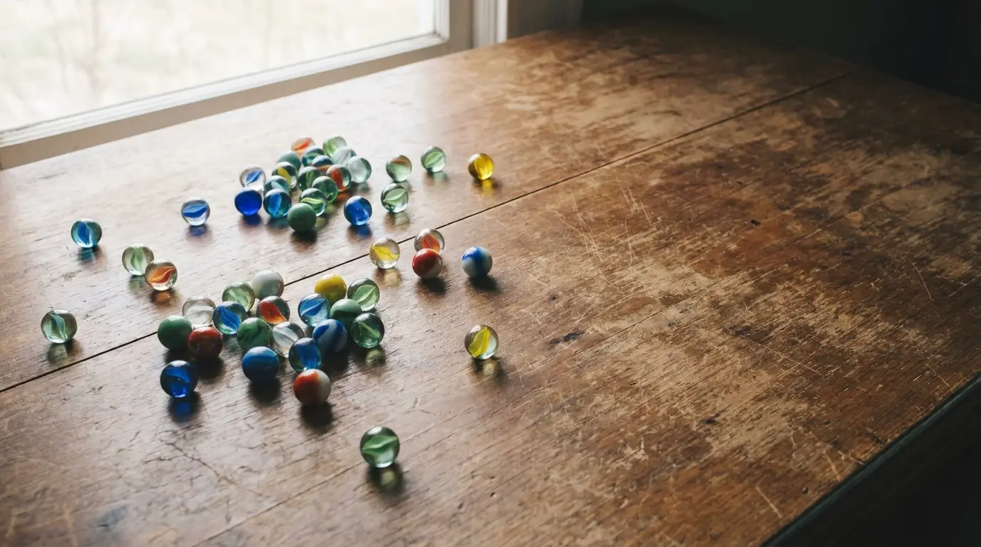 Colorful glass marbles scattered on rustic wooden table by a window