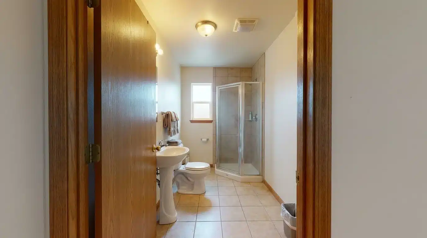 compact three quarter bathroom layout with a sink toilet corner shower and open doorway view