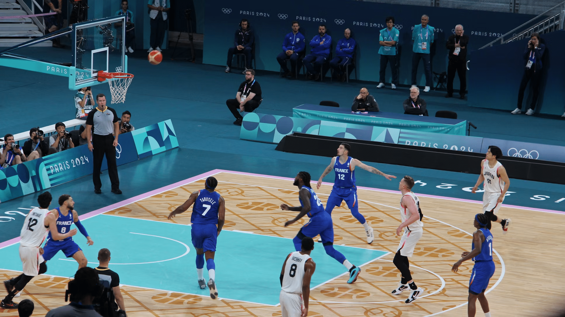 Basketball players from France and Japan in blue and white uniforms during a game at Paris 2024